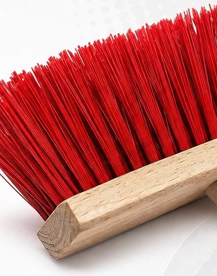 Cabeça de vassoura doméstica com cerdas de monofilamento vermelho, em close.
